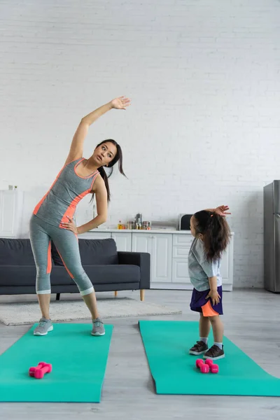 Madre asiática e hijo haciendo ejercicio en colchonetas de fitness en casa - foto de stock