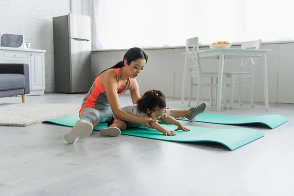 Young asian woman stretching with toddler child at home — Stock Photo