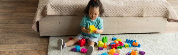 Asian child playing building blocks on carpet, banner — Stock Photo