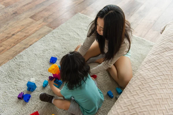 Vista aerea di madre e figlia asiatica che giocano mattoni su tappeto — Foto stock