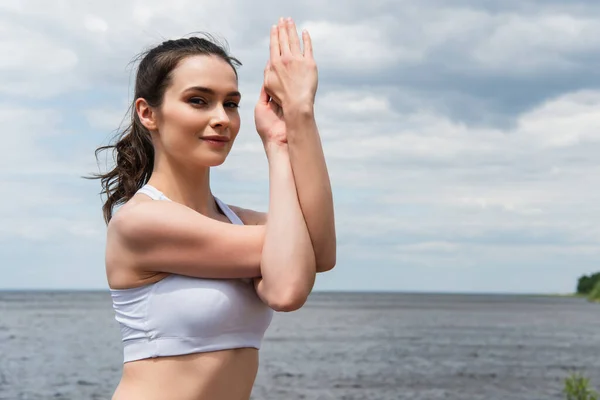 Happy brunette woman practicing arms exercise near sea — Stock Photo