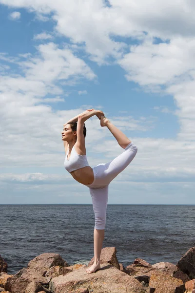 Full length of sportive woman in lord of dance pose near sea — Stock Photo