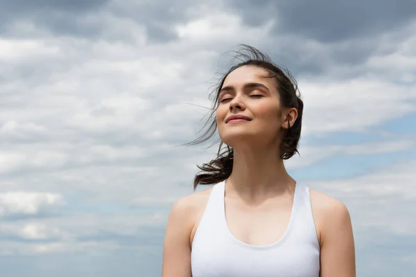 Jovem mulher satisfeita no topo da colheita contra o céu azul com nuvens — Fotografia de Stock