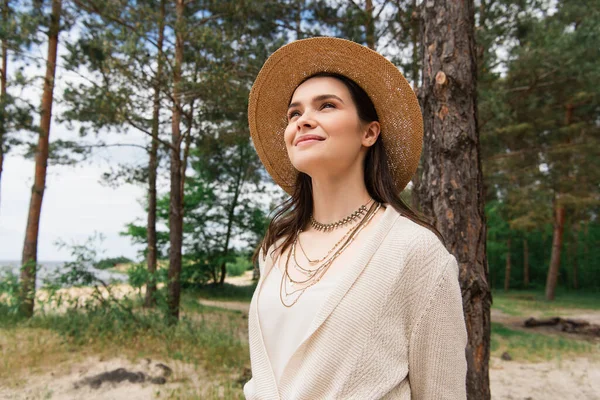 Cheerful young woman in sun hat smiling in forest — Stock Photo