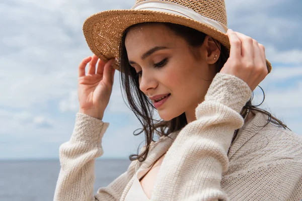 Cheerful young woman adjusting sun hat outside — Stock Photo