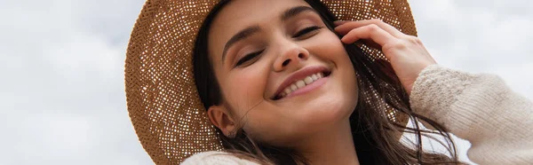 Tiefansicht einer glücklichen jungen Frau mit Strohhut, die in die Kamera blickt, Banner — Stockfoto