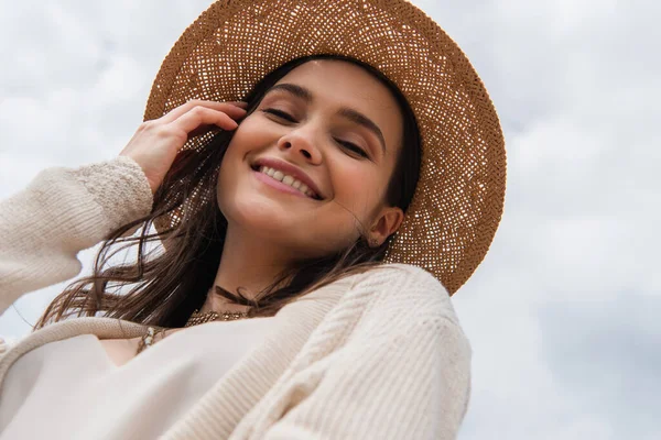 Baixo ângulo vista de alegre jovem mulher em chapéu de palha olhando para a câmera — Fotografia de Stock