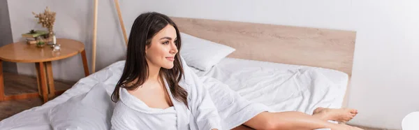 Задоволена жінка в халаті лежить на ліжку вдома, банер — стокове фото