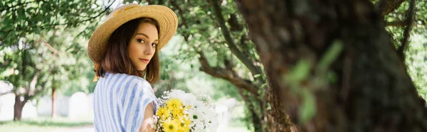 Young woman in straw hat holding bouquet in park, banner — Stock Photo