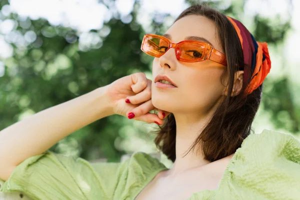 Low angle view of woman in sunglasses looking at camera outdoors — Stock Photo