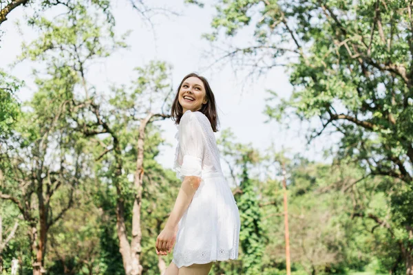 Mulher feliz em vestido branco de pé no parque de verão — Fotografia de Stock