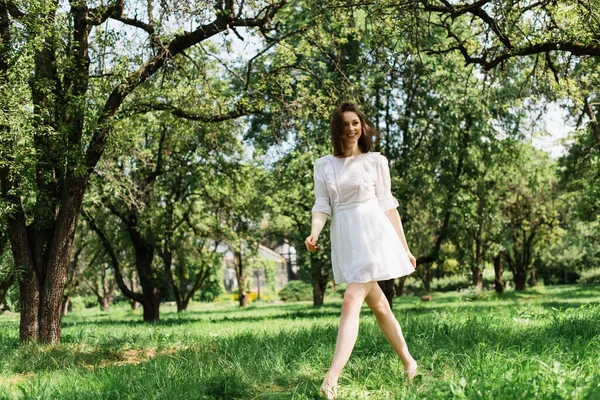 Mulher alegre no vestido de verão andando na grama no parque — Fotografia de Stock