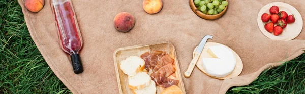 Vista superior de delicioso queso, vino y frutas en manta de picnic, pancarta - foto de stock