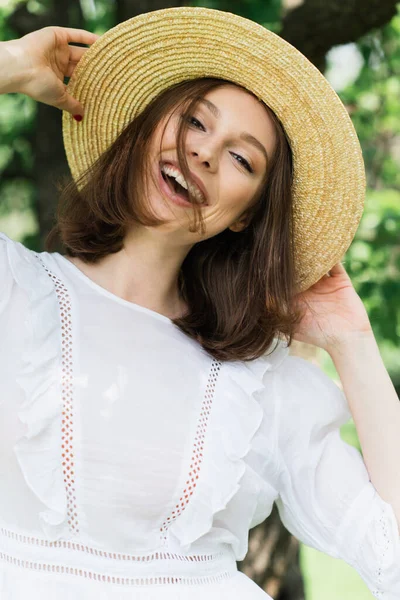 Donna sorridente che tiene il cappello da sole nel parco — Foto stock