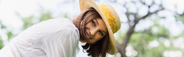 Mujer bonita en sombrero de sol mirando hacia otro lado en el parque de verano, pancarta - foto de stock