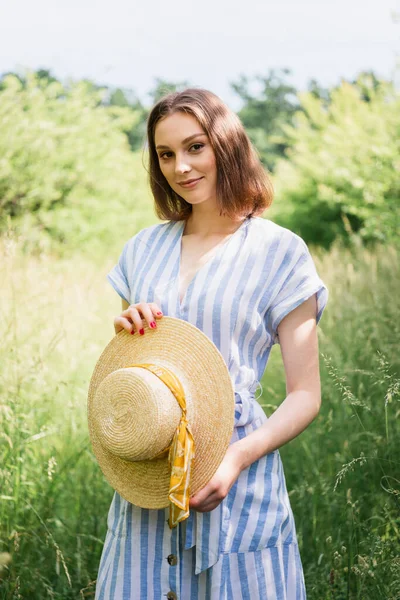 Красивая женщина, держащая шляпу в парке летом — стоковое фото