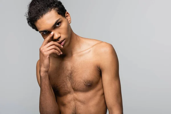 Joven, hombre afroamericano sin camisa de pie con la mano cerca de la cara aislado en gris, concepto de belleza - foto de stock