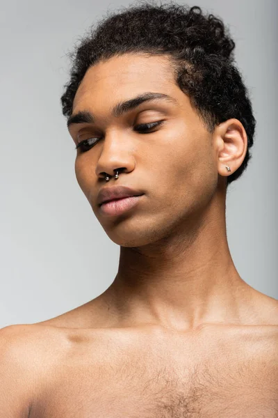 Портрет молодого африканского американца с чистой кожей и пирсингом, изолированный на сером, концепция красоты — стоковое фото