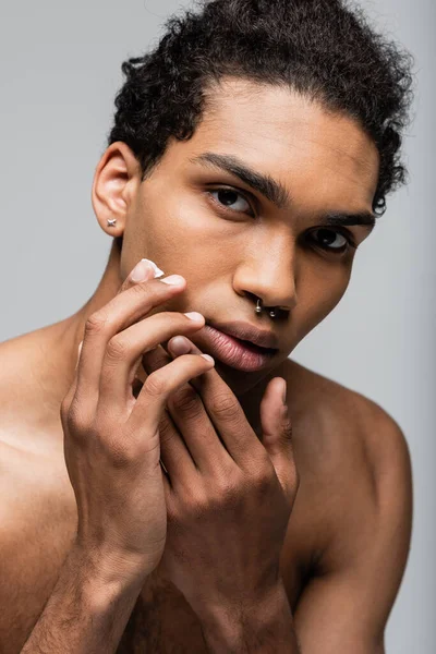 Piercing afro-americano homem aplicando creme facial isolado no cinza — Fotografia de Stock