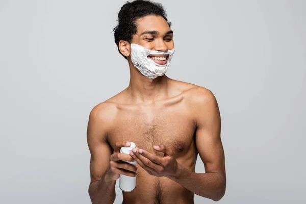 Uomo afroamericano sorridente che tiene il contenitore con schiuma da barba isolata su grigio — Foto stock