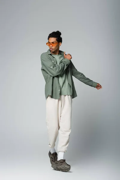 Full length view of african american man in shirt and white pants posing on grey background — Stock Photo