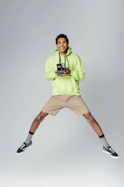Excité homme afro-américain lévitant avec caméra vintage isolé sur gris — Photo de stock