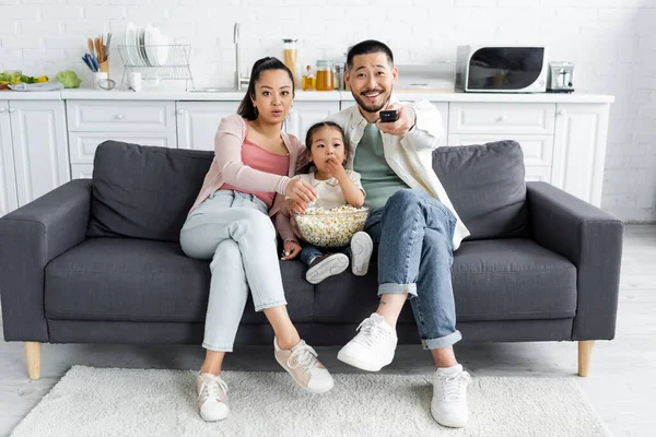 Asian family watching tv and eating popcorn in living room — Stock Photo