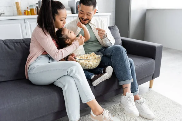 Glückliche asiatische Familie isst Popcorn im Wohnzimmer — Stockfoto