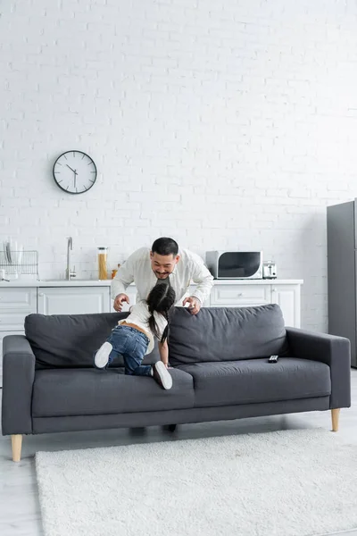 Cheerful asian father playing with toddler daughter at home — Stock Photo