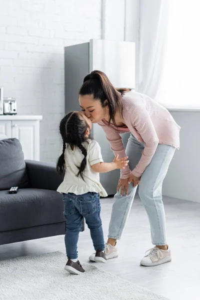 Asian mother kissing toddler child at home — Stock Photo