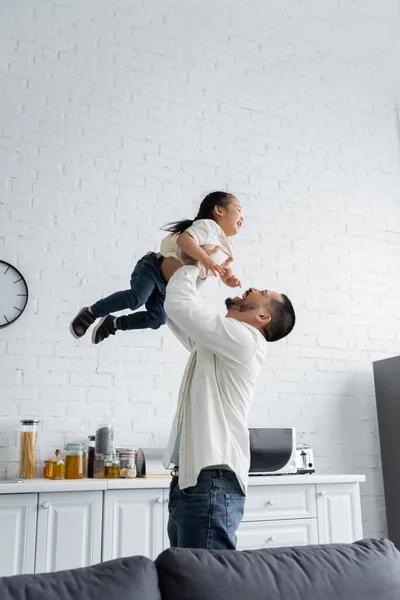 Fröhliche asiatische Vater hält in den Armen Kleinkind Mädchen zu Hause — Stockfoto