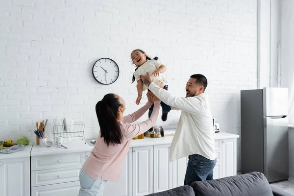 Alegre asiático pai segurando em braços filha perto feliz esposa — Fotografia de Stock