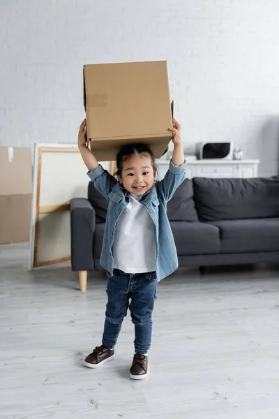 Happy asian toddler girl holding carton box in new home — Stock Photo