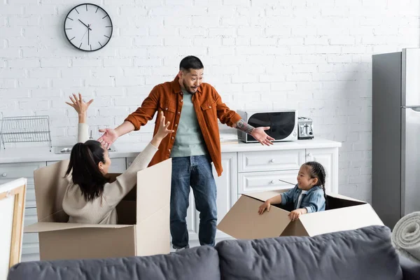Amazed asian man looking at wife and daughter hiding in boxes — Stock Photo