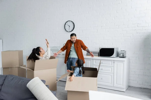 Asian woman and kid in boxes scaring man in new home — Stock Photo