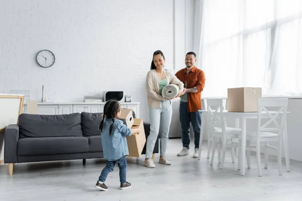 Happy asian parents looking at toddler daughter with boxes — Stock Photo
