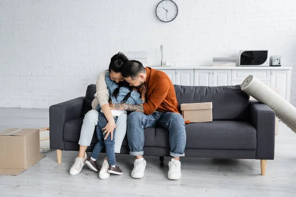 Asiático familia abrazando cerca cajas en nuevo hogar - foto de stock