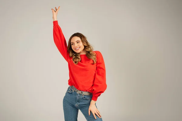 Mujer feliz en sudadera mirando hacia otro lado y bailando aislado en gris - foto de stock