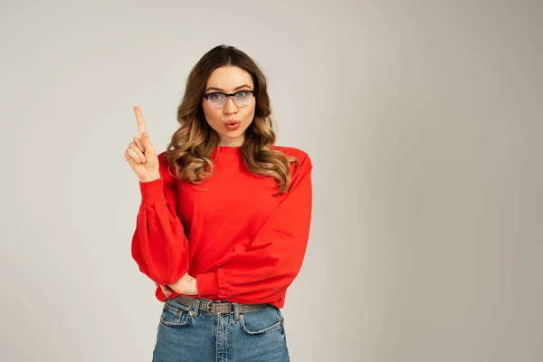 Shocked woman with duck face pointing with finger isolated on grey — Stock Photo