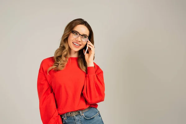 Gioiosa donna in occhiali che parla su smartphone isolato su grigio — Foto stock