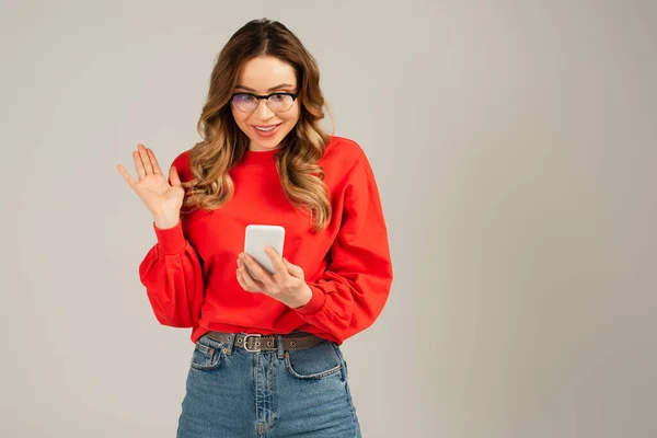 Glückliche Frau in Brille mit Videoanruf auf Smartphone isoliert auf grau — Stockfoto