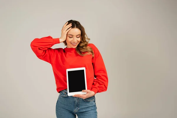 Mujer alegre mirando la tableta digital con la pantalla en blanco aislada en gris — Stock Photo