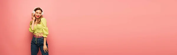 Fröhliche Frau stellt drahtlose Kopfhörer auf rosa ein, Banner — Stockfoto