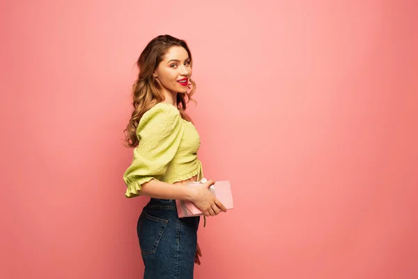 Pleased woman holding wrapped present isolated on pink — Stock Photo