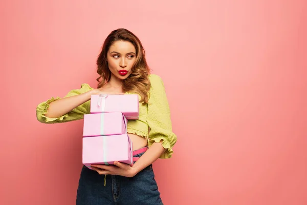 Frau mit Entengesicht hält verpackte Geschenkboxen isoliert auf rosa — Stockfoto