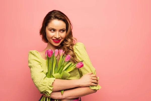 Mujer alegre sosteniendo ramo de tulipanes aislados en rosa - foto de stock