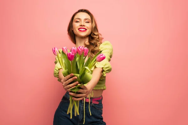 Femme floue et heureuse tenant bouquet de tulipes isolées sur rose — Photo de stock