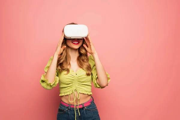 Mujer feliz en auriculares vr sonriendo aislado en rosa - foto de stock