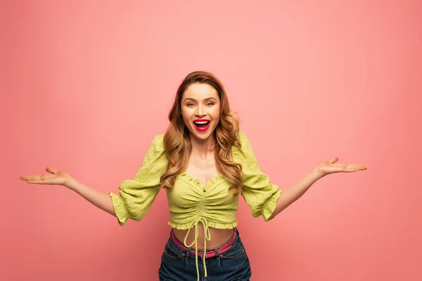 Cheerful woman with outstretched hands and open mouth isolated on pink — Stock Photo