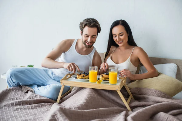 Coppia allegra che fa colazione a letto — Foto stock